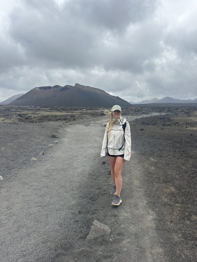 Eleonora cammina lungo una strada di lava scura, il vulcano alle spalle
