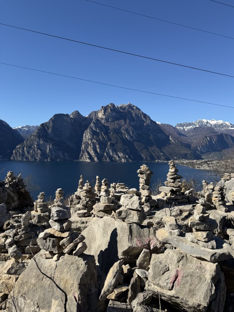 Ometti di pietra sulla riva del lago, montagne innevate sullo sfondo